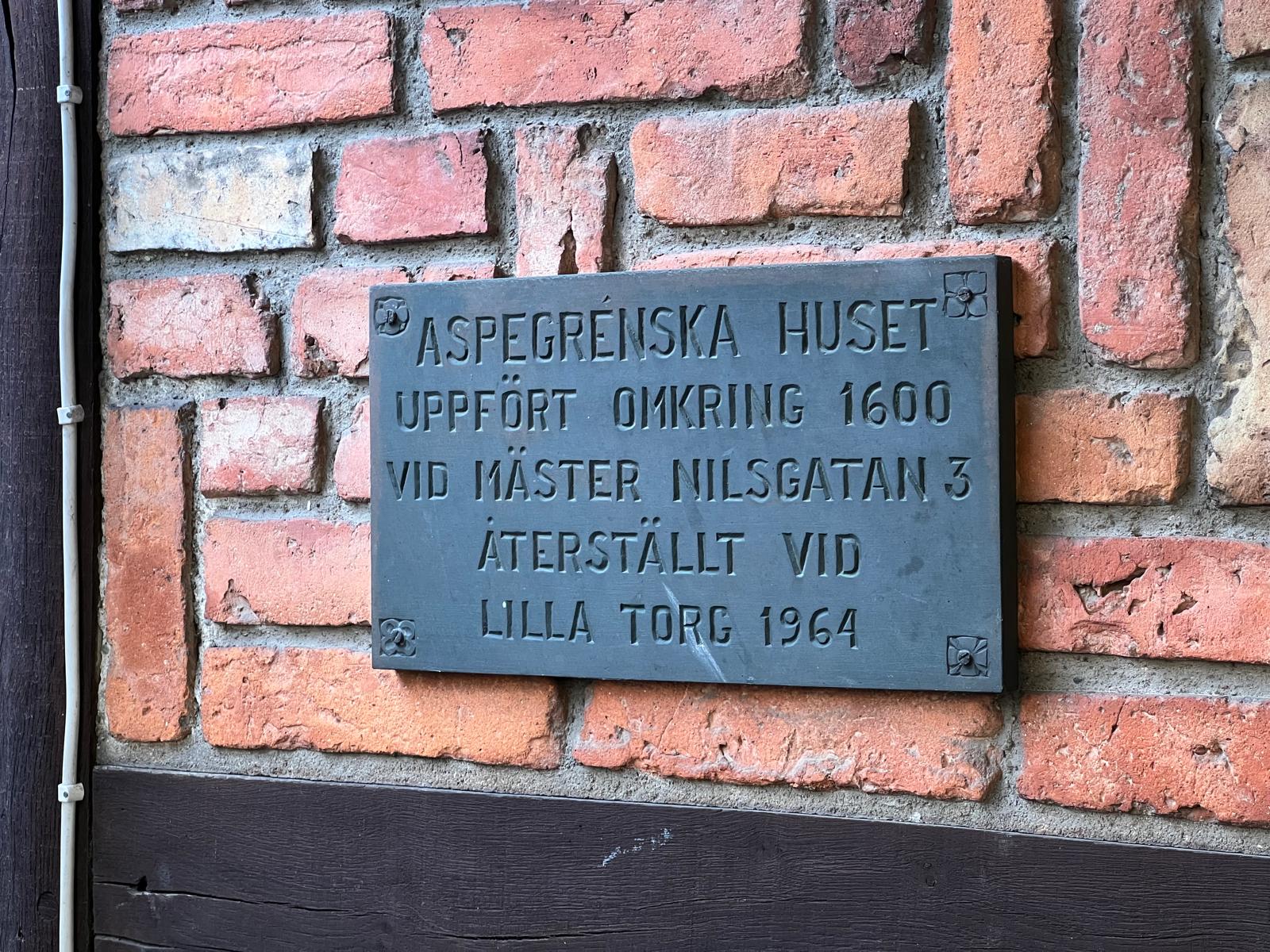 Skylt på Aspegrenska husets tegelfasad vid Lilla Torg i Malmö